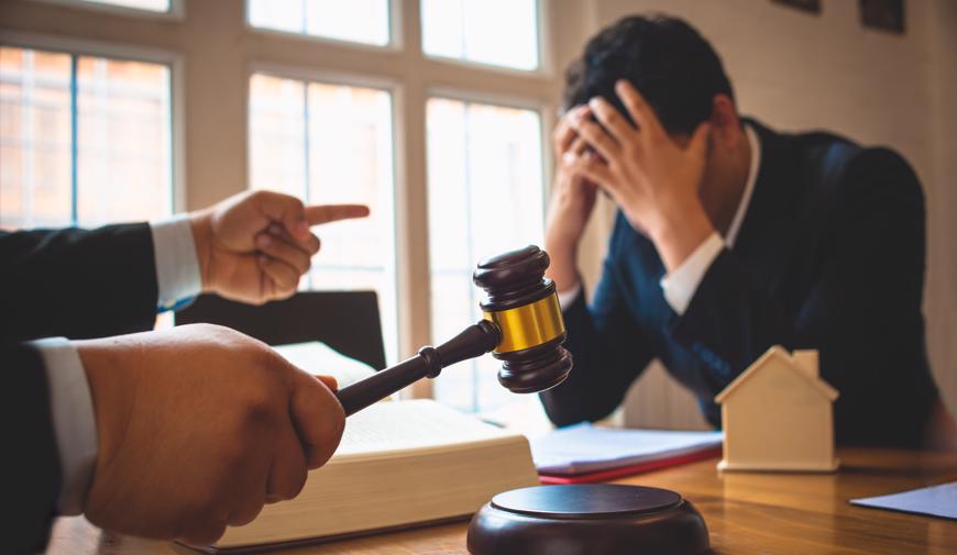 this image shows a stressed man sitting across a desk from a judge.