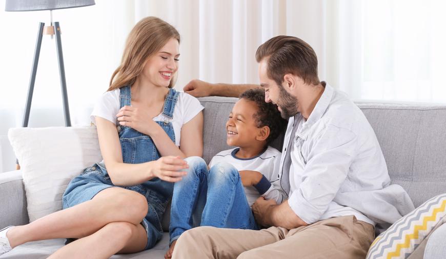 this image shows a couple and their adopted child on a couch.